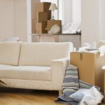 A living room with sofa surrounded by cardboard boxes as if someone is moving in.