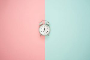 a clock on a pink-green wall