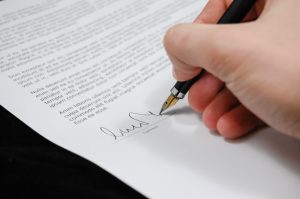 A person signing a contract document.