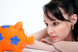 A woman looking at a piggy bank, wondering how much to tip movers.
