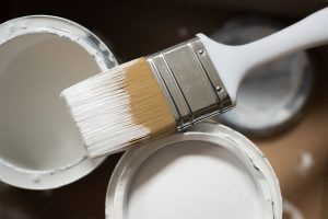 a paint brush and two cans of white paint