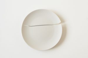 a white, broken plate on a white surface
